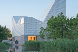  » Vermittelt zwischen Erde und Himmel: Das Kirchenzentrum Seliger Pater Rupert Mayer in Poing bei München. meck Architekten verkleideten den oberen, himmelwärts gerichteten Teil des Gebäudes mit geschwungenen Keramikfliesen, die als  Lichtreflektoren fungieren. Das Gebäude war 2020 für den Brick Award in der Kategorie Building outside the box nominiert. 