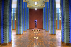  » Ausstellungshalle mit Bronzefigur „Aufbruch“ von Richard Scheibe. Sie zeigt einen Arbeiter, der sich entschlossen die Ärmel hochkrempelt  