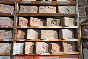  »Fig. 8: For example, the sequence of characters MMP on the tile on the fourth shelf on the far right stands for Markt Mistelbach, where -bach is spelt with a p. On the shelf below you can see prints of a chicken, cat and dog 