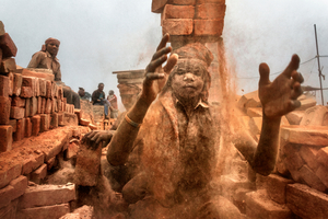 » Kathmandu-Tal, Nepal 2018. Ein junger Arbeiter lädt Ziegelsteine auf seinen Kopf; der Staub, der von den Ziegelsteinen aufgewirbelt wird, verursacht schwere Erkrankungen der Lunge 
