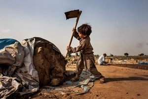  » Pakistan 2025. Ein Kind zerteilt einen Tonhaufen mit der Hacke 
