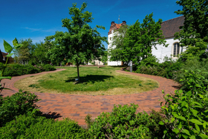  » Rundwege fassen den grünen Teil des Kirchvorplatzes ein, hier mit Blick auf das Pfarramtshaus (Hintergrund links) 