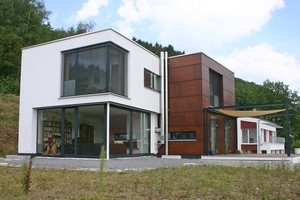  &gt;&gt; Das Haus am Stadtrand von Plettenberg liegt in direkter Nähe zu einem Naturpark. Seine Fassade fügt sich mit dem weißen Scheibenputz und den Mahagoni-Holztafeln harmonisch in die benachbarte „grüne“ Naturlandschaft ein.  