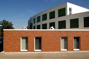  &gt;&gt; Material mix of clay bricks and white facades structured with glass blocks. The footballs on the roof cover the ventilation shafts 